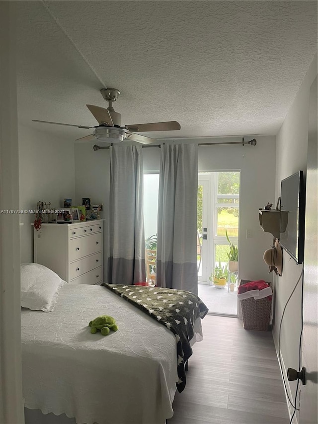 bedroom featuring ceiling fan, access to exterior, a textured ceiling, and light hardwood / wood-style flooring