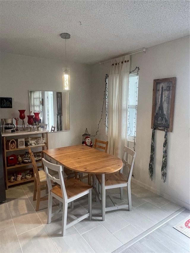 dining area featuring light tile patterned floors and a textured ceiling