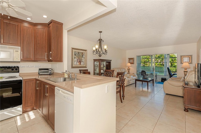 kitchen with white appliances, sink, light tile patterned floors, a textured ceiling, and kitchen peninsula