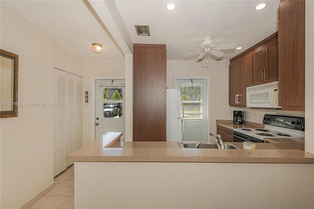 kitchen featuring white appliances, sink, ceiling fan, light tile patterned flooring, and kitchen peninsula