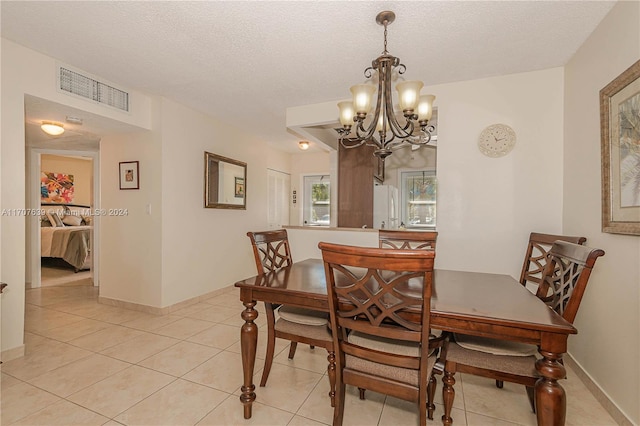 dining space featuring a chandelier, a textured ceiling, and light tile patterned flooring