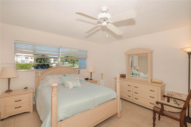 bedroom with ceiling fan, light tile patterned floors, and a textured ceiling