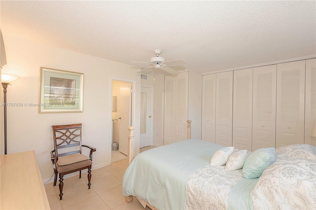 tiled bedroom with ceiling fan, a textured ceiling, and two closets