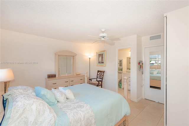 tiled bedroom featuring a textured ceiling, ceiling fan, and ensuite bathroom