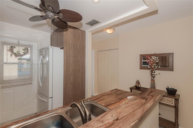 kitchen featuring ceiling fan, white fridge, sink, and wooden counters