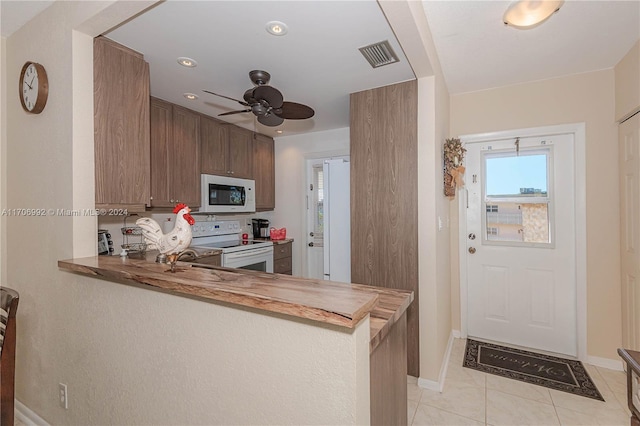 kitchen with kitchen peninsula, ceiling fan, light tile patterned floors, and white appliances