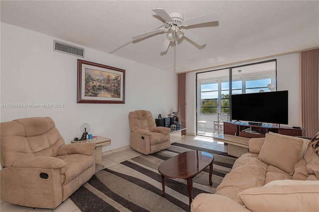 living room featuring ceiling fan, light tile patterned flooring, and a textured ceiling