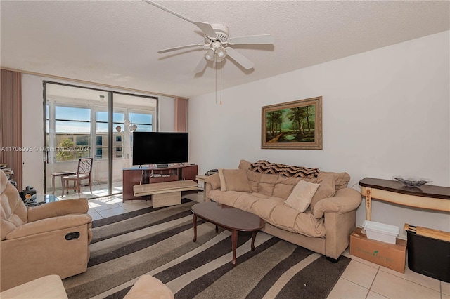 living room featuring ceiling fan, light tile patterned floors, a textured ceiling, and a wall of windows