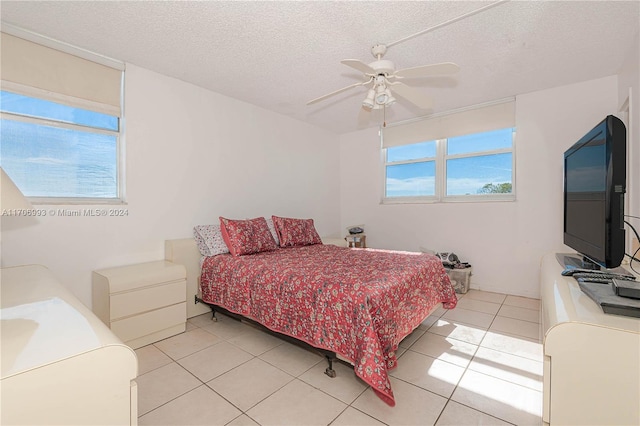 bedroom with light tile patterned floors, a textured ceiling, multiple windows, and ceiling fan