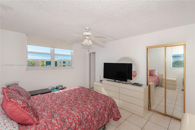 tiled bedroom with ceiling fan and a textured ceiling