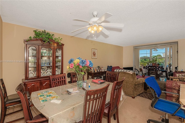 dining area featuring a textured ceiling, light colored carpet, and ceiling fan