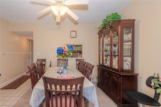 tiled dining space featuring a textured ceiling and ceiling fan