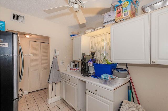 kitchen with stainless steel refrigerator, ceiling fan, light tile patterned flooring, a textured ceiling, and white cabinets