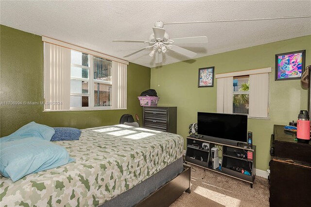 bedroom featuring ceiling fan, carpet floors, a textured ceiling, and multiple windows