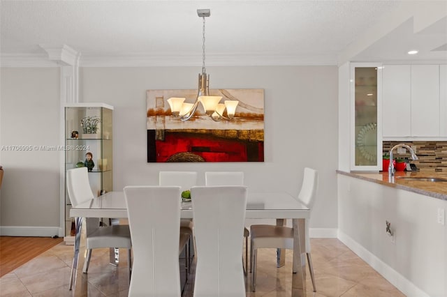 dining room with ornamental molding, a textured ceiling, sink, light tile patterned floors, and a notable chandelier