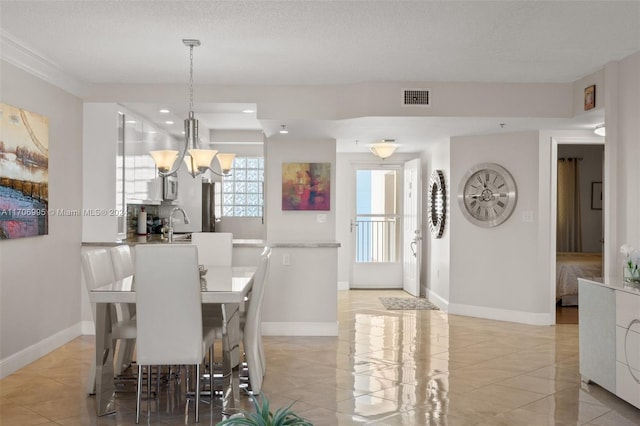 dining space featuring a textured ceiling, an inviting chandelier, and sink