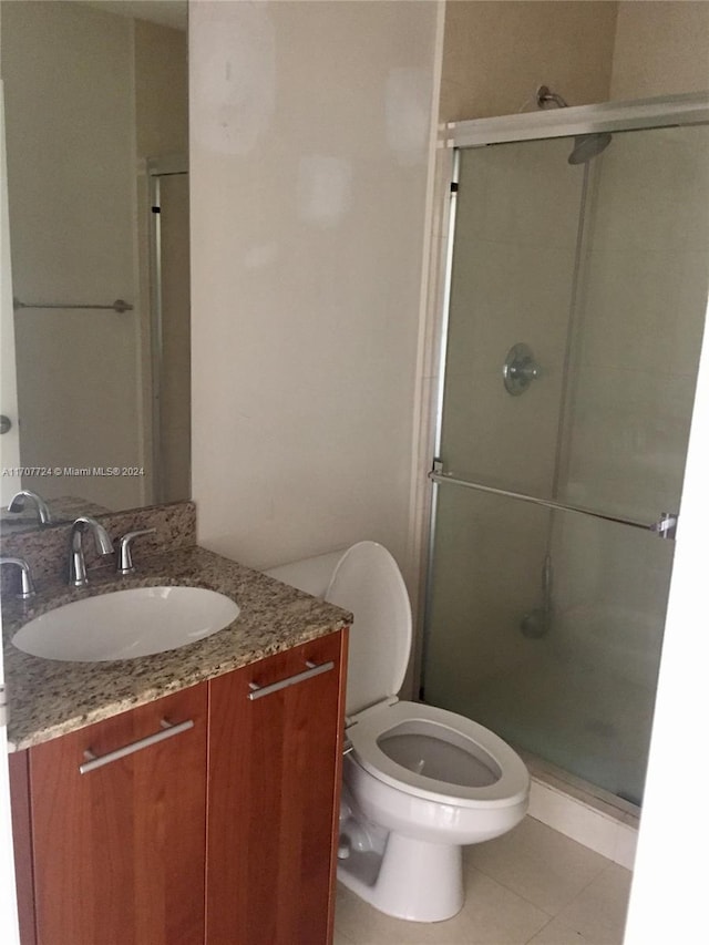 bathroom with tile patterned flooring, vanity, an enclosed shower, and toilet