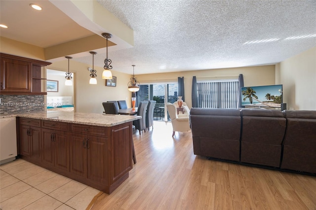 kitchen featuring white dishwasher, hanging light fixtures, decorative backsplash, light wood-type flooring, and kitchen peninsula