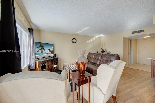 living room featuring light wood-type flooring and a textured ceiling