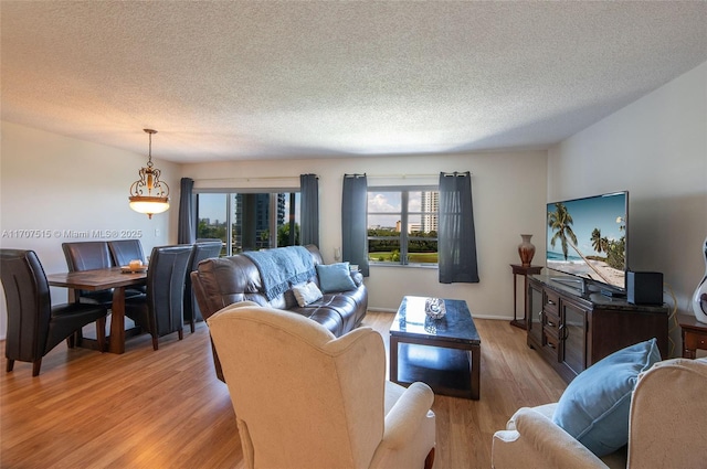 living room featuring baseboards, light wood-style floors, and a textured ceiling