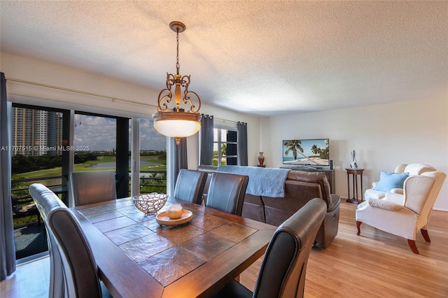 dining area with a textured ceiling and wood finished floors