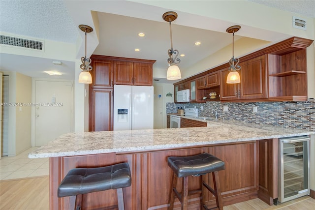 kitchen featuring light wood-type flooring, white appliances, kitchen peninsula, and beverage cooler