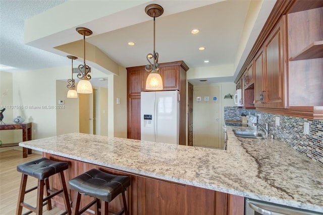 kitchen featuring kitchen peninsula, light wood-type flooring, tasteful backsplash, hanging light fixtures, and white fridge with ice dispenser