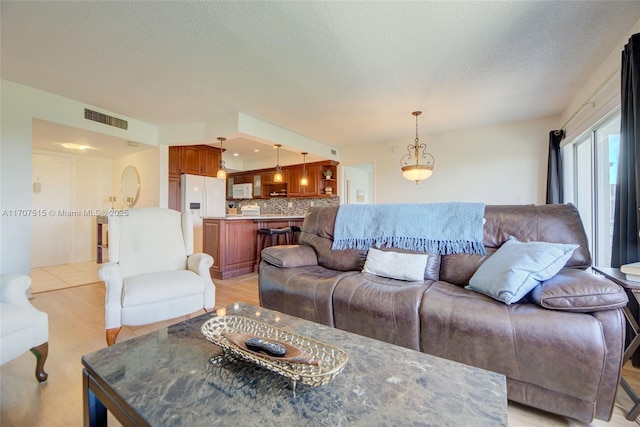 living area with a textured ceiling and visible vents