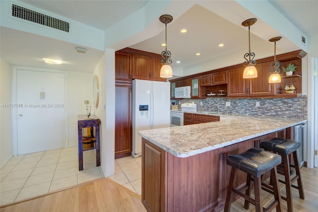 kitchen featuring open shelves, white appliances, light stone countertops, visible vents, and a peninsula