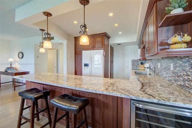 kitchen featuring a peninsula, white appliances, a sink, open shelves, and beverage cooler