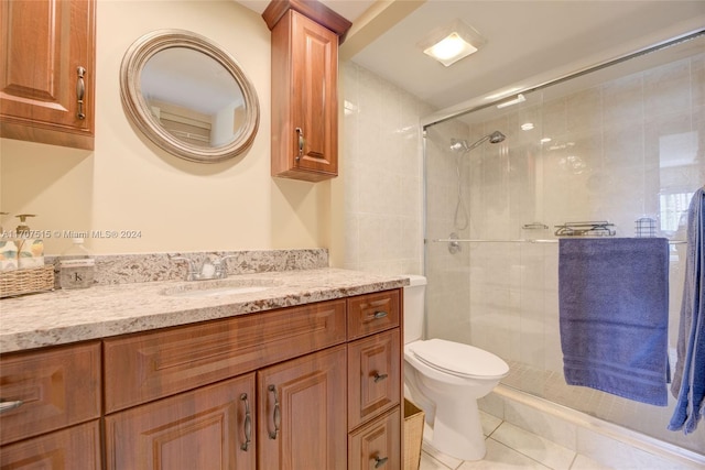 bathroom featuring toilet, vanity, tile patterned floors, and a shower with door