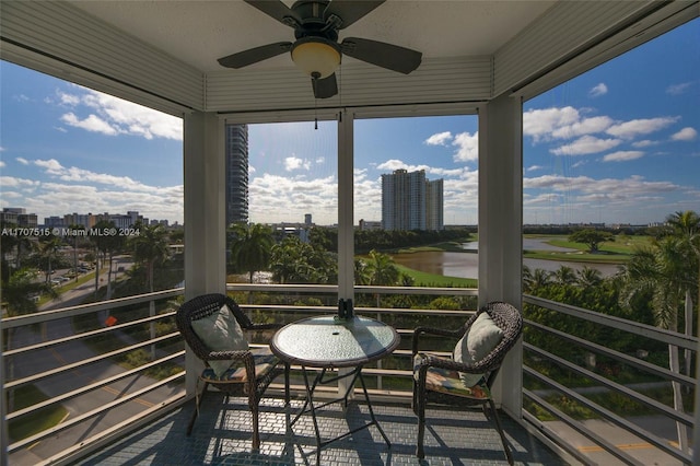 sunroom / solarium featuring a water view and ceiling fan