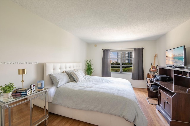 bedroom featuring light wood finished floors and a textured ceiling