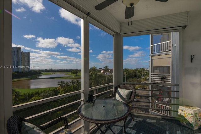 sunroom featuring ceiling fan, plenty of natural light, and a water view