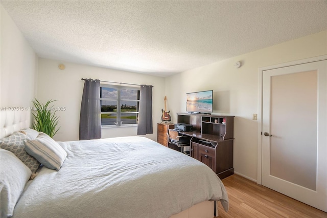 bedroom with a textured ceiling and light wood-style floors