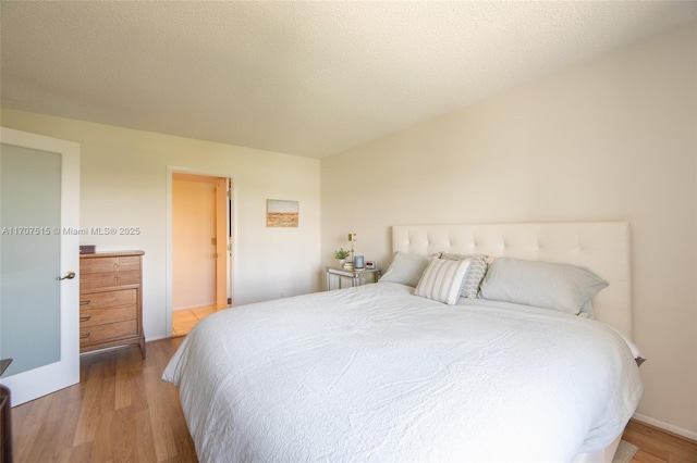bedroom with a textured ceiling and wood finished floors