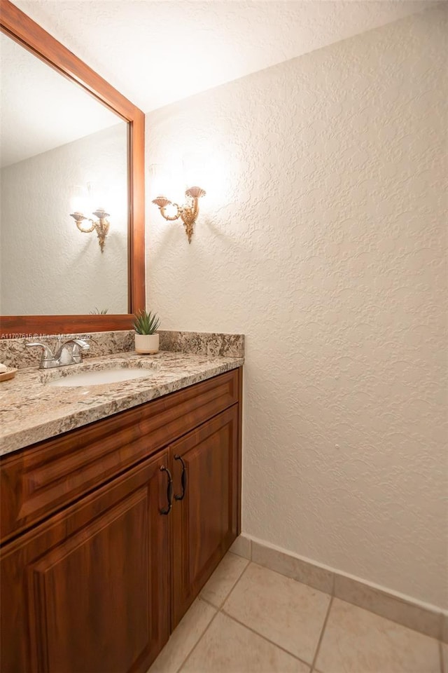 bathroom with tile patterned floors, vanity, a textured wall, and baseboards