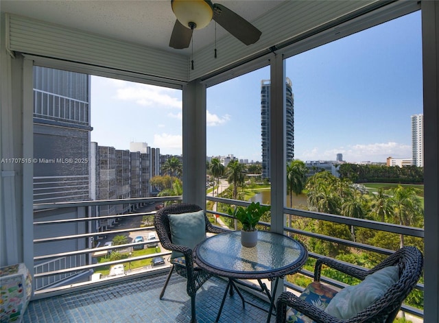 sunroom featuring a city view and ceiling fan