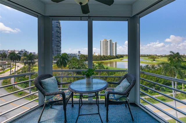 balcony with a ceiling fan, a water view, and a city view