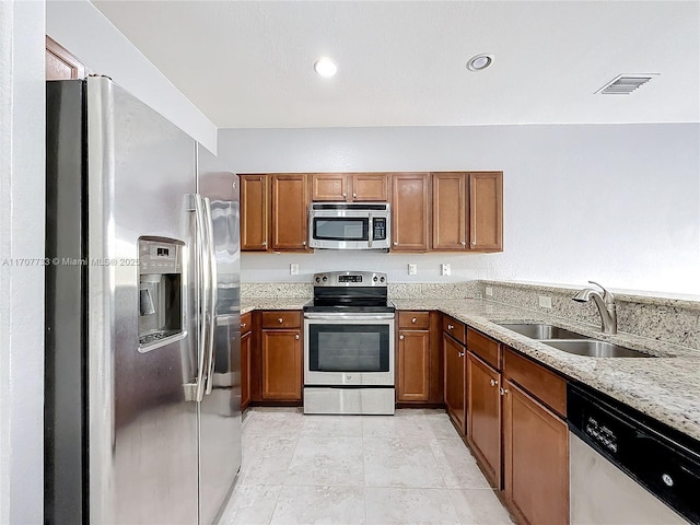 kitchen with light tile patterned flooring, appliances with stainless steel finishes, light stone countertops, and sink