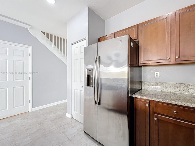 kitchen featuring light stone counters, light tile patterned floors, and stainless steel fridge