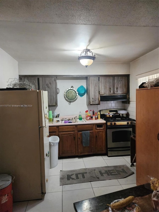 317 NW 3rd St, Deerfield Beach, FL 33441 - kitchen with tasteful backsplash, gas range, sink, light tile patterned floors, and white refrigerator