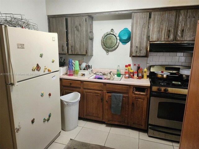 317 NW 3rd St, Deerfield Beach, FL 33441 - kitchen with sink, white refrigerator, black range with gas cooktop, dark brown cabinets, and light tile patterned flooring
