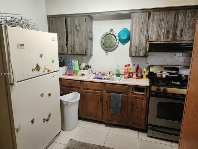 317 NW 3rd St, Deerfield Beach, FL 33441 - kitchen featuring freestanding refrigerator, gas range, range hood, light tile patterned floors, and light countertops