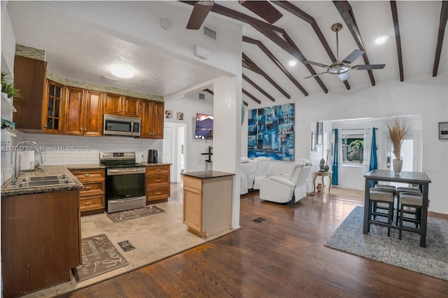 kitchen with appliances with stainless steel finishes, backsplash, sink, vaulted ceiling with beams, and light hardwood / wood-style floors