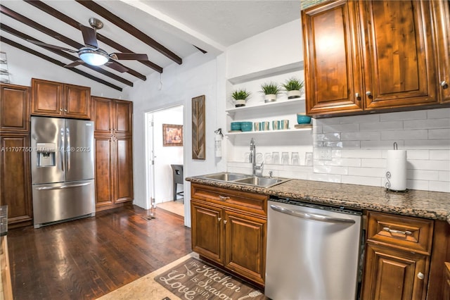 kitchen with backsplash, lofted ceiling with beams, sink, dark stone countertops, and stainless steel appliances