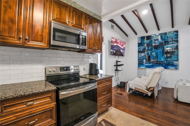 kitchen featuring dark stone counters, lofted ceiling with beams, light tile patterned floors, appliances with stainless steel finishes, and tasteful backsplash