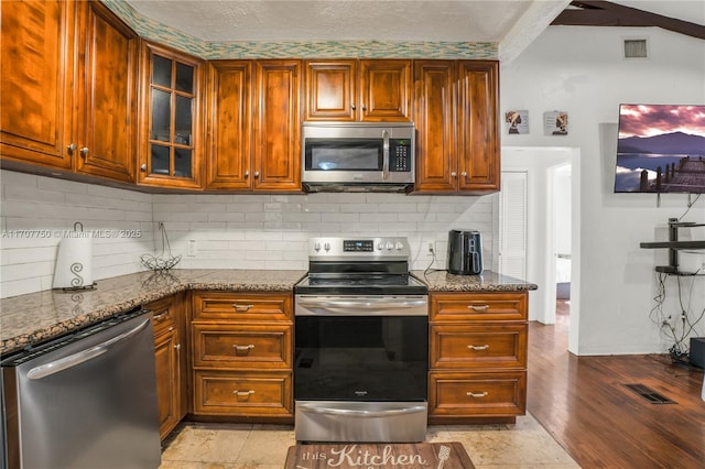 kitchen with dark stone counters, tasteful backsplash, and stainless steel appliances