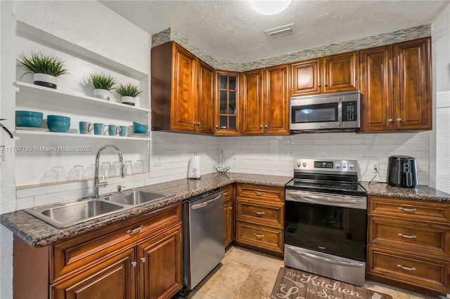 kitchen featuring sink, tasteful backsplash, dark stone countertops, a textured ceiling, and appliances with stainless steel finishes