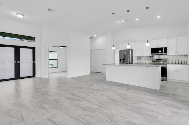 kitchen featuring high vaulted ceiling, ceiling fan, a kitchen island, and appliances with stainless steel finishes